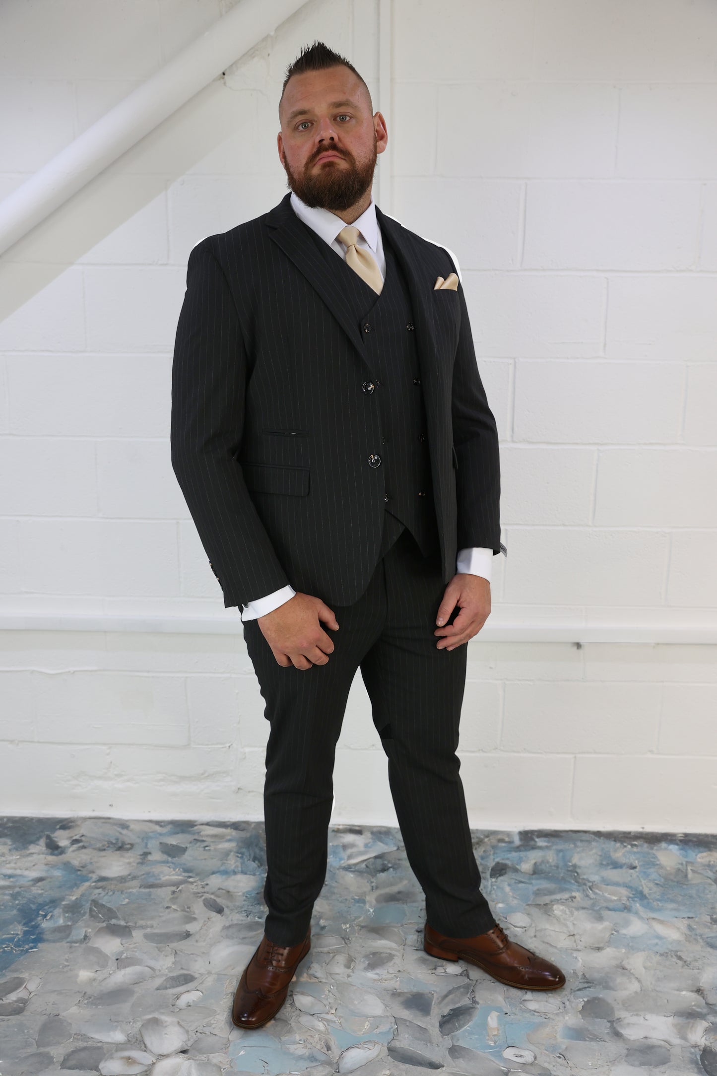Model wearing the SUITBAE Black Pinstripe Three Piece Suit — slim-fit pinstripe blazer, matching waistcoat and trousers, paired with a white shirt, gold tie and pocket square — a sharp look for weddings, business, or formal occasions — available at SUITBAE Blackpool, Barnsley and SUITBAE.com.