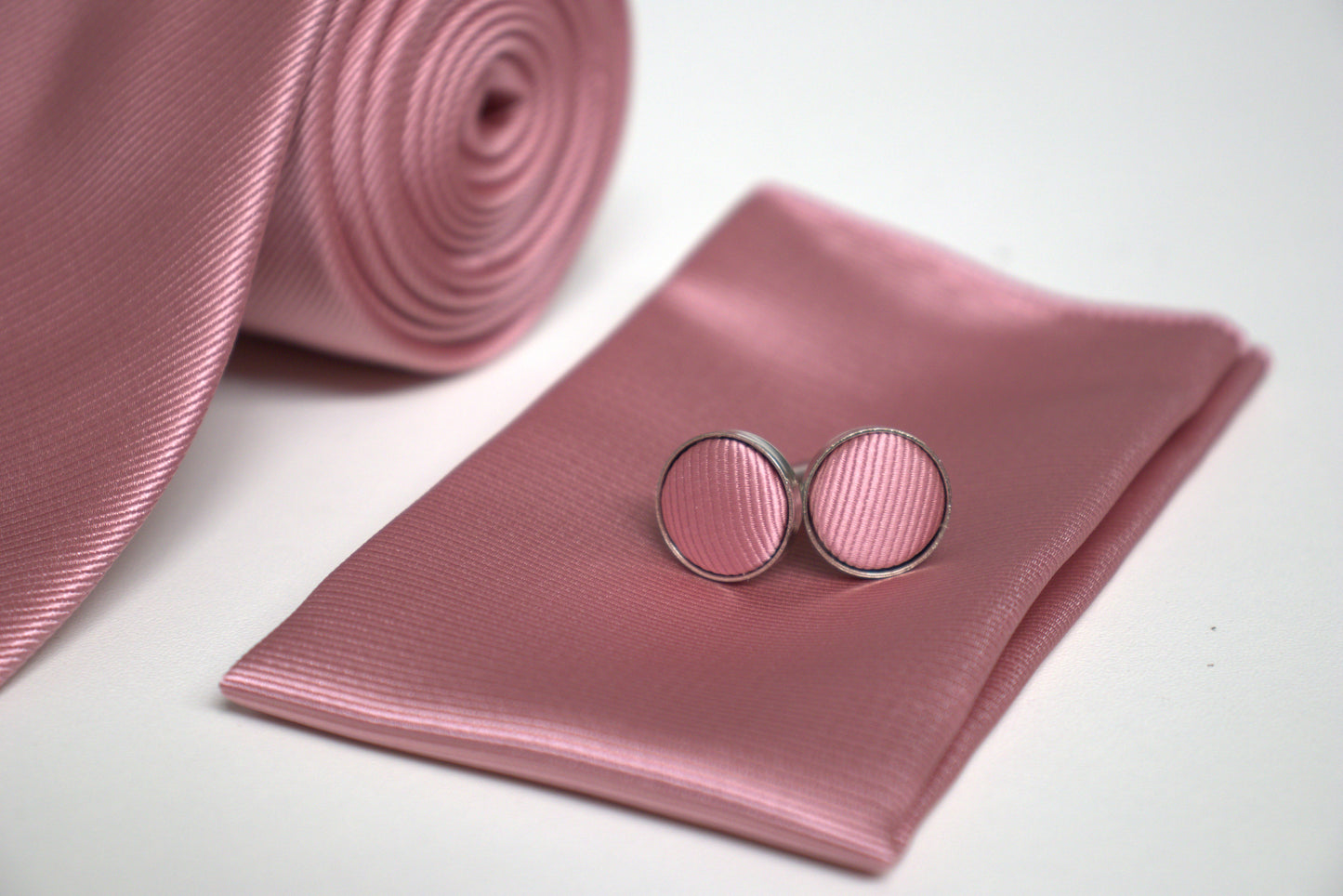 Close-up of mauve pink tie set with cufflinks on matching pocket square, stylish groomsmen accessories for formal occasions