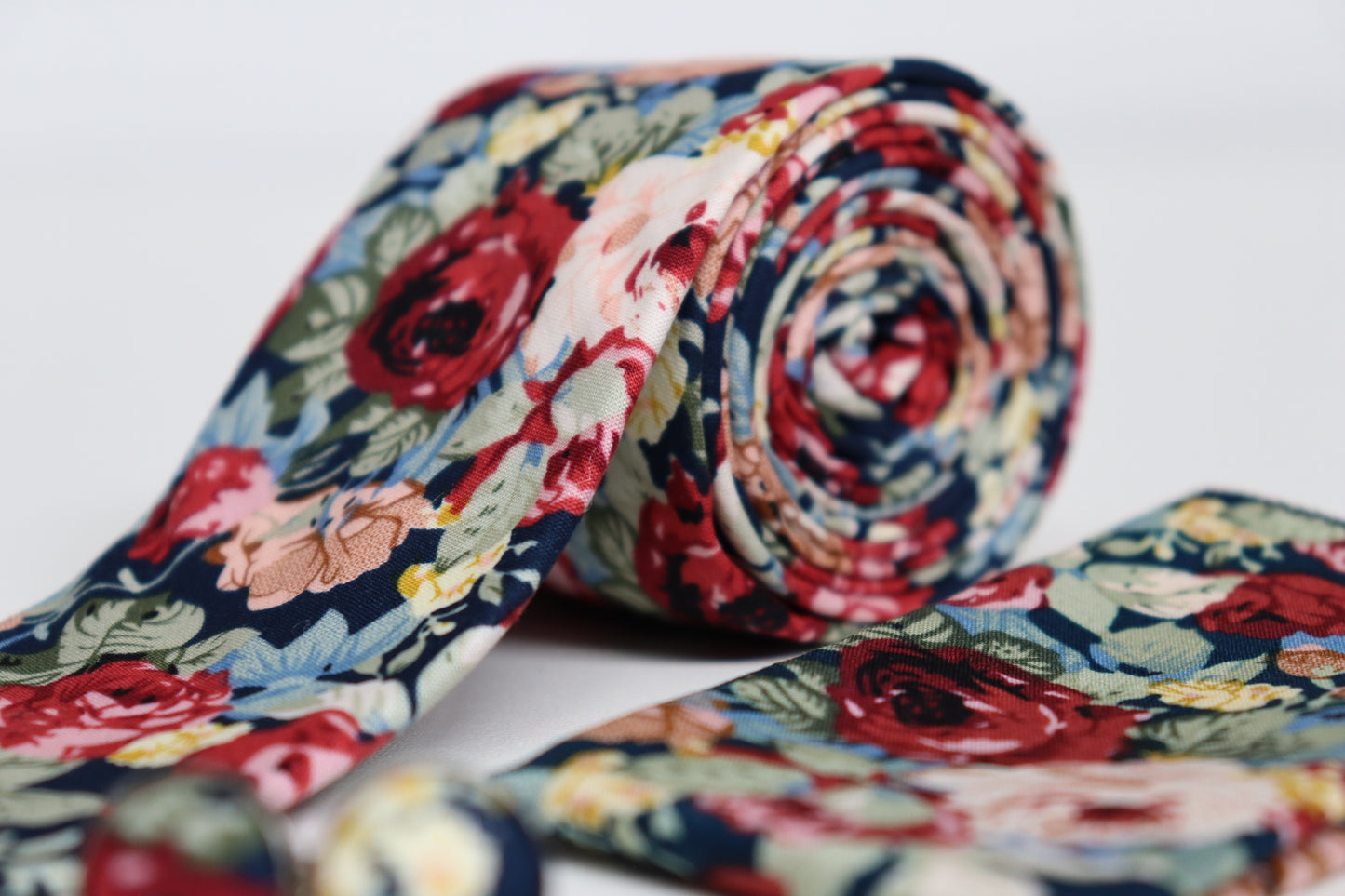 Close-up of navy floral tie with red, pink and beige flowers, elegant men’s accessory for weddings and summer races
