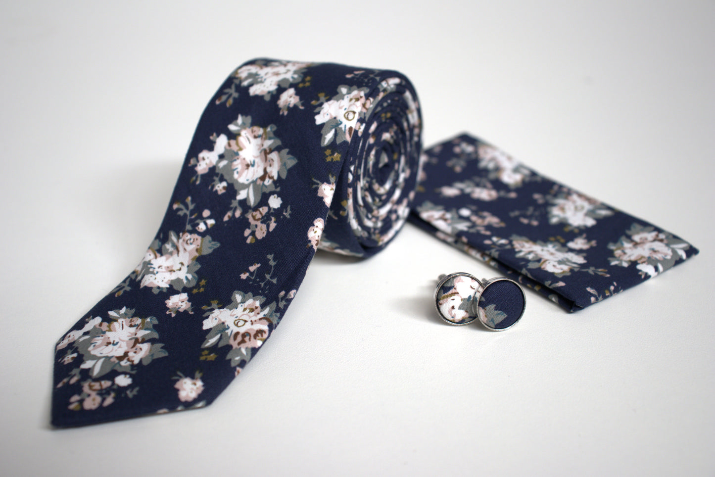 Close-up of navy floral tie with pocket square and cufflinks, stylish accessory set for grooms and formal occasions