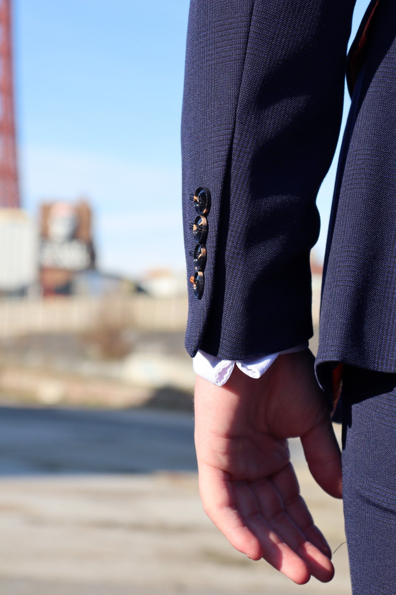 Close-up of the sleeve on the SUITBAE Charles Navy Three-Piece Suit showing the dark navy textured fabric, tortoiseshell buttons, and precise tailoring. A refined finish that defines SUITBAE craftsmanship — available in plus sizes.