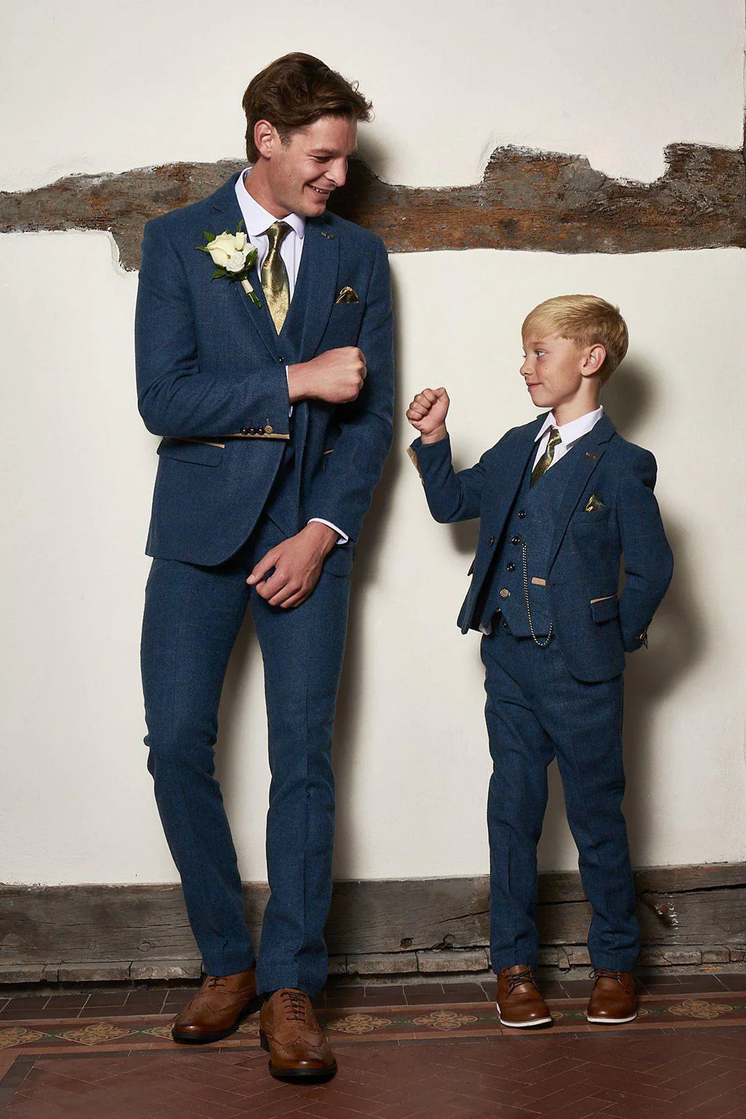 Father and son wearing matching blue three-piece suits with brown shoes, perfect for weddings and formal family events