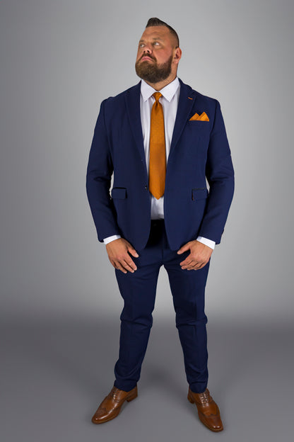 This image shows a man confidently dressed in a navy check three-piece suit, paired with an eye-catching orange tie and pocket square. The well-tailored suit, complete with a crisp white shirt, strikes a perfect balance between formal elegance and modern style. The brown leather shoes complete the sophisticated look, making this outfit ideal for formal occasions, business meetings, or weddings. The overall ensemble demonstrates a powerful sense of fashion with a contemporary twist.