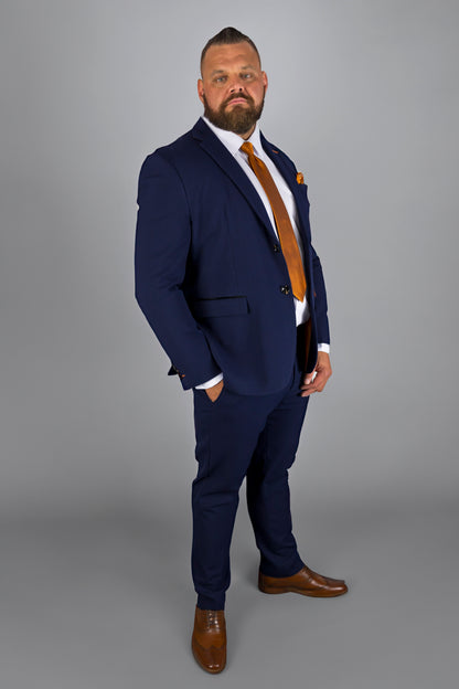 This image shows a man confidently posing in a tailored navy check three-piece suit, paired with a bold orange tie and matching pocket square. The outfit is complemented by a crisp white shirt and brown leather shoes. The modern fit and sleek design make this ensemble perfect for formal events or business settings. The orange accents add a vibrant touch to the classic navy suit, showcasing a stylish and contemporary look for the fashion-forward individual.