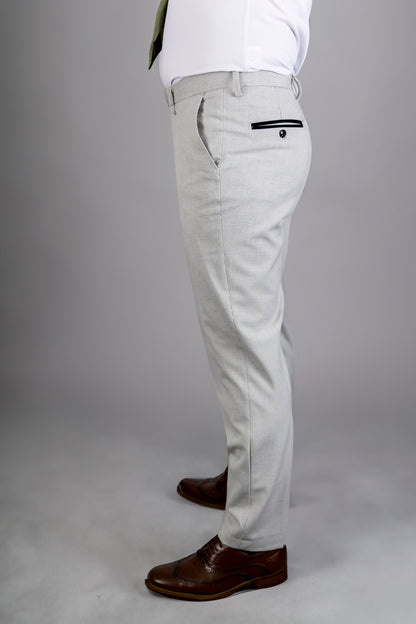 Side view of Suitbae Charles stone trousers in a tailored fit, highlighting the sharp silhouette and subtle Prince of Wales check pattern. The trousers feature a contrasting black buttoned back pocket, adding a stylish detail. Paired with classic brown brogue shoes, this look exudes elegance and sophistication, perfect for formal and business occasions.