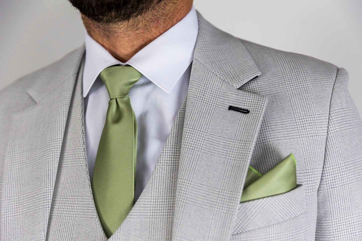 Close-up of the Suitbae Charles stone suit with a Prince of Wales check pattern, featuring a light green tie and matching pocket square. The tailored lapel and sharp detailing offer a refined look, perfect for big and tall sizes seeking a sophisticated style.