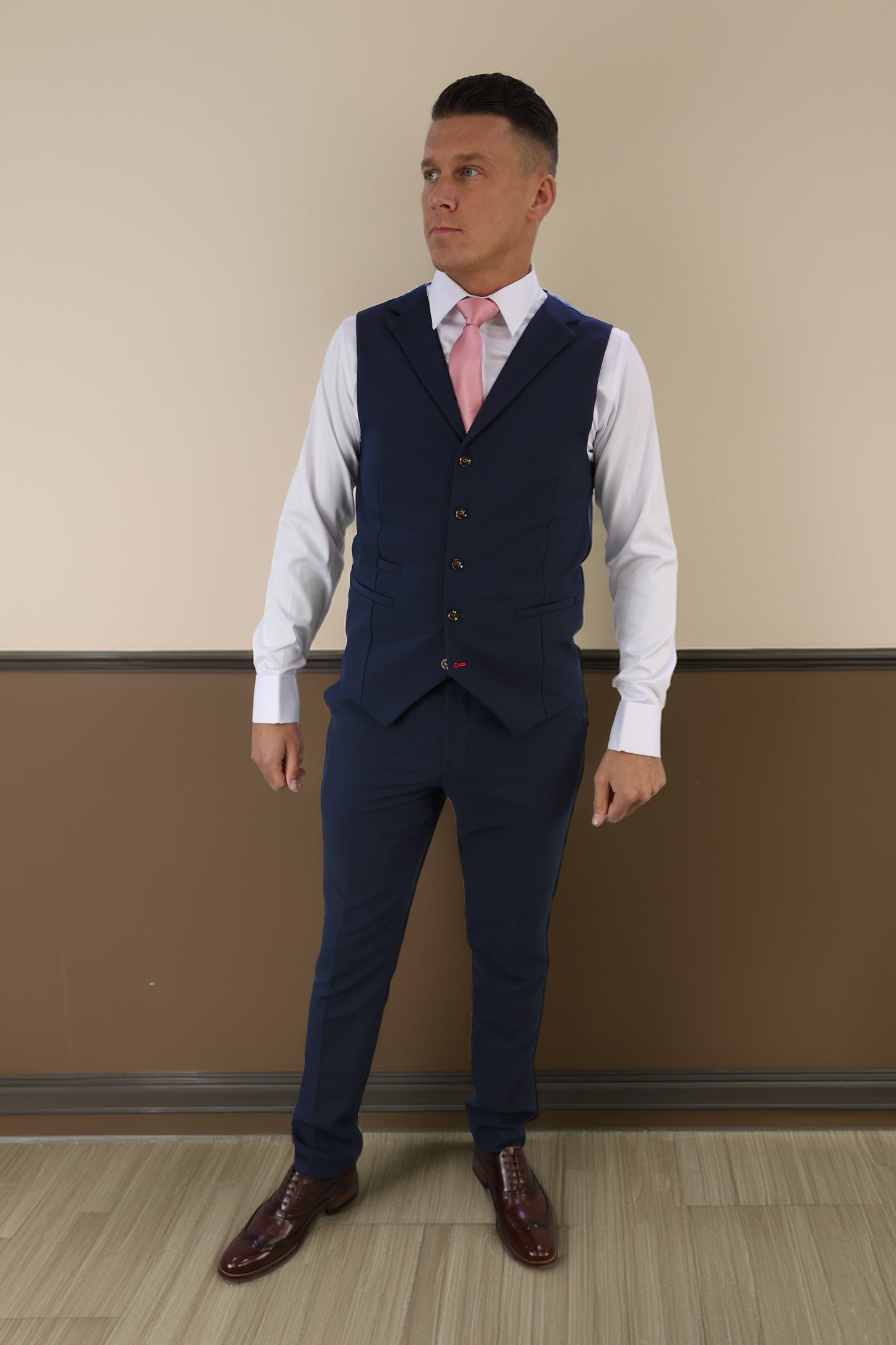 Model wearing a navy waistcoat and trousers paired with a white shirt and pink tie, styled with brown leather shoes. Designed for XL, Plus Size, and Big & Tall men's sizes. Available at Suitbae.com