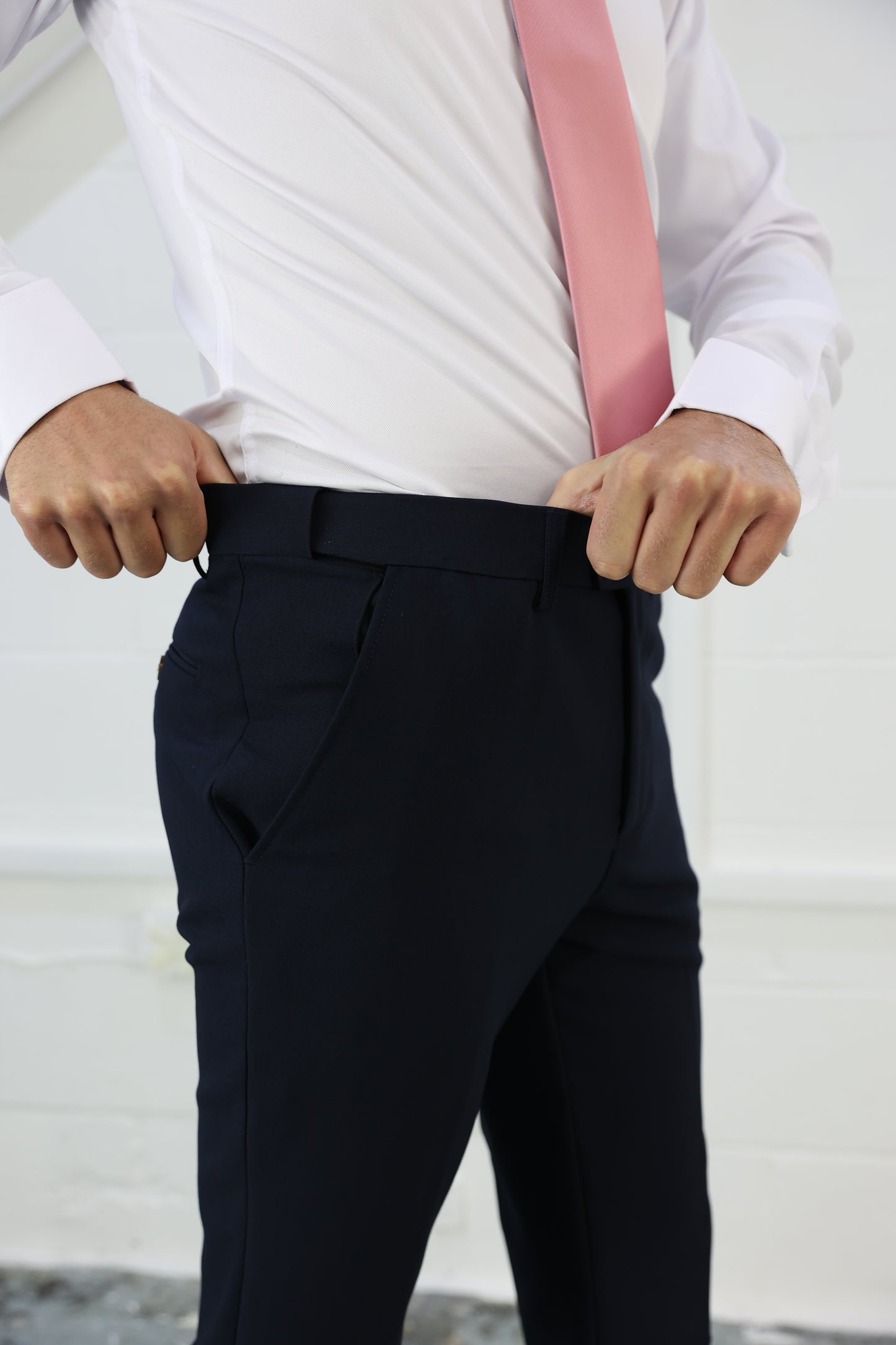 Close-up of navy trousers with a stretch waistband, paired with a white shirt and pink tie. Designed for comfort and fit in XL, Plus Size, and Big & Tall men's sizes. Available at Suitbae.com