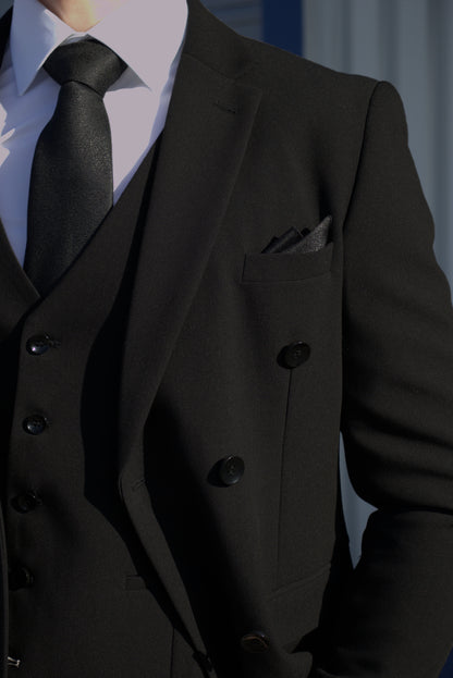 Close-up of the SUITBAE Diablo Black Double Breasted Three-Piece Suit, showing the waistcoat and blazer combination with black buttons, a white shirt, black tie, and matching black pocket square for a polished formal look.