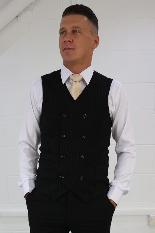 Man wearing a Suitbae black pinstripe double-breasted waistcoat, paired with a white shirt and gold tie; available in skinny fit, slim fit, tailored fit, plus size, larger men's, and big & tall sizes, perfect for formal and smart-casual occasions.