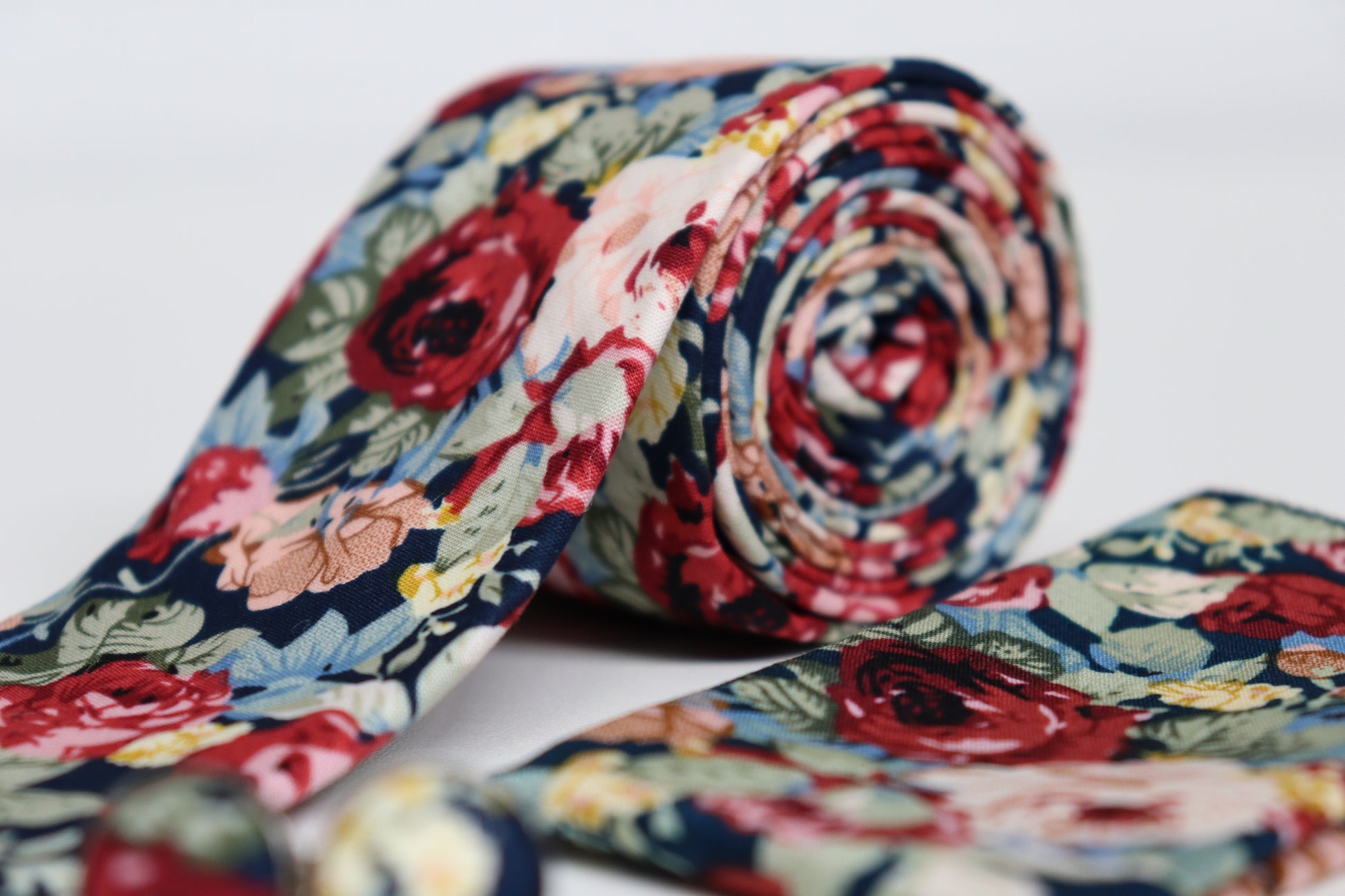 Close-up of navy floral tie with red, pink and beige flowers, elegant men’s accessory for weddings and summer races