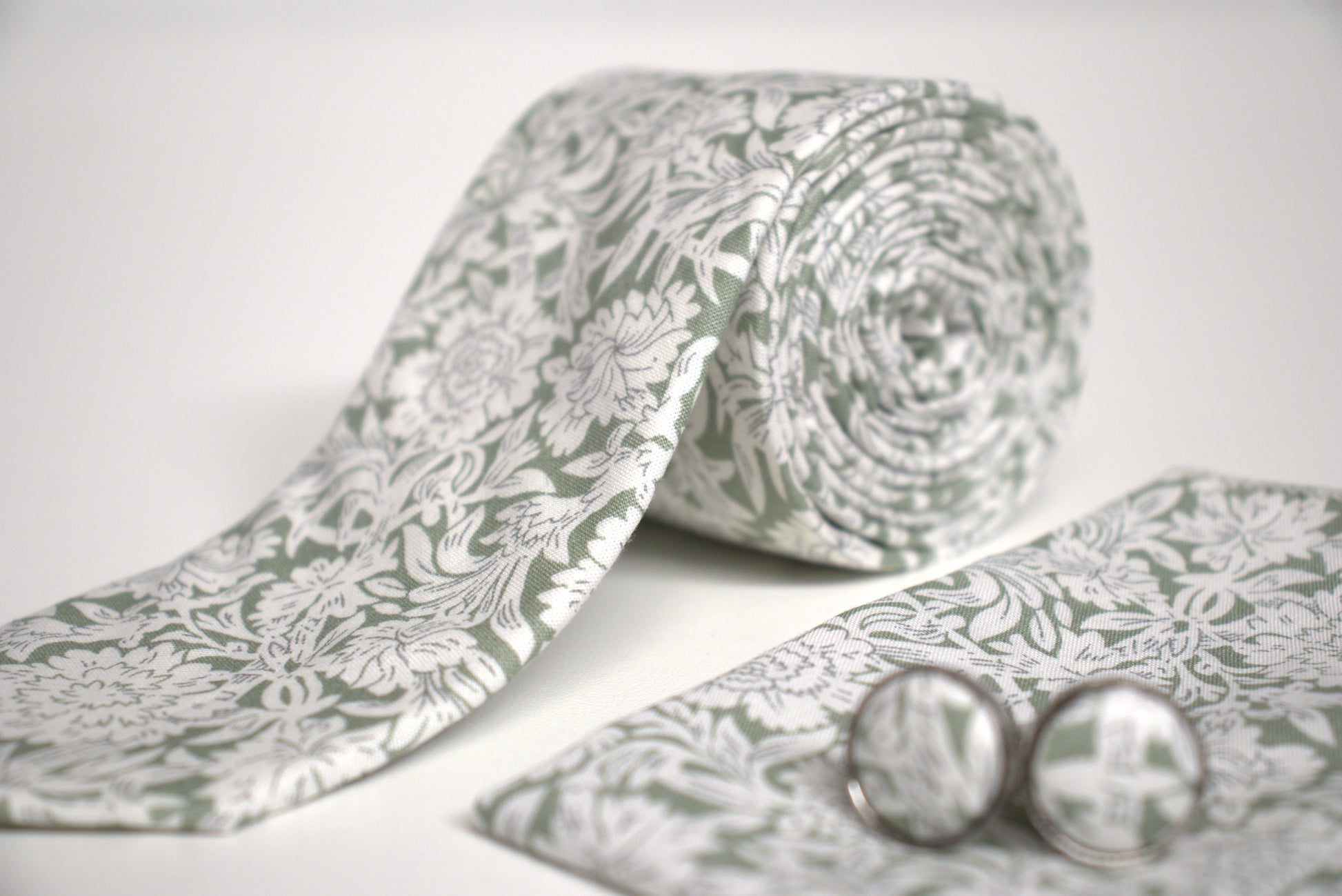 Detailed view of sage green and white floral tie fabric, elegant men’s accessory for weddings, races and summer proms