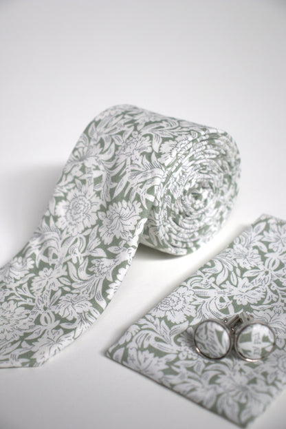Close-up of sage green floral tie with pocket square and cufflinks, stylish groomsmen accessory for weddings, proms and formal occasions