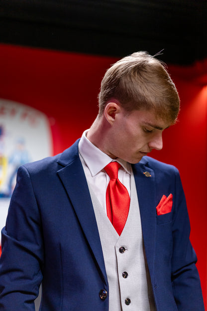 Man wearing the SUITBAE Charles Navy Three-Piece Suit with a bright red tie and matching pocket square, photographed indoors at Barnsley Football Club.