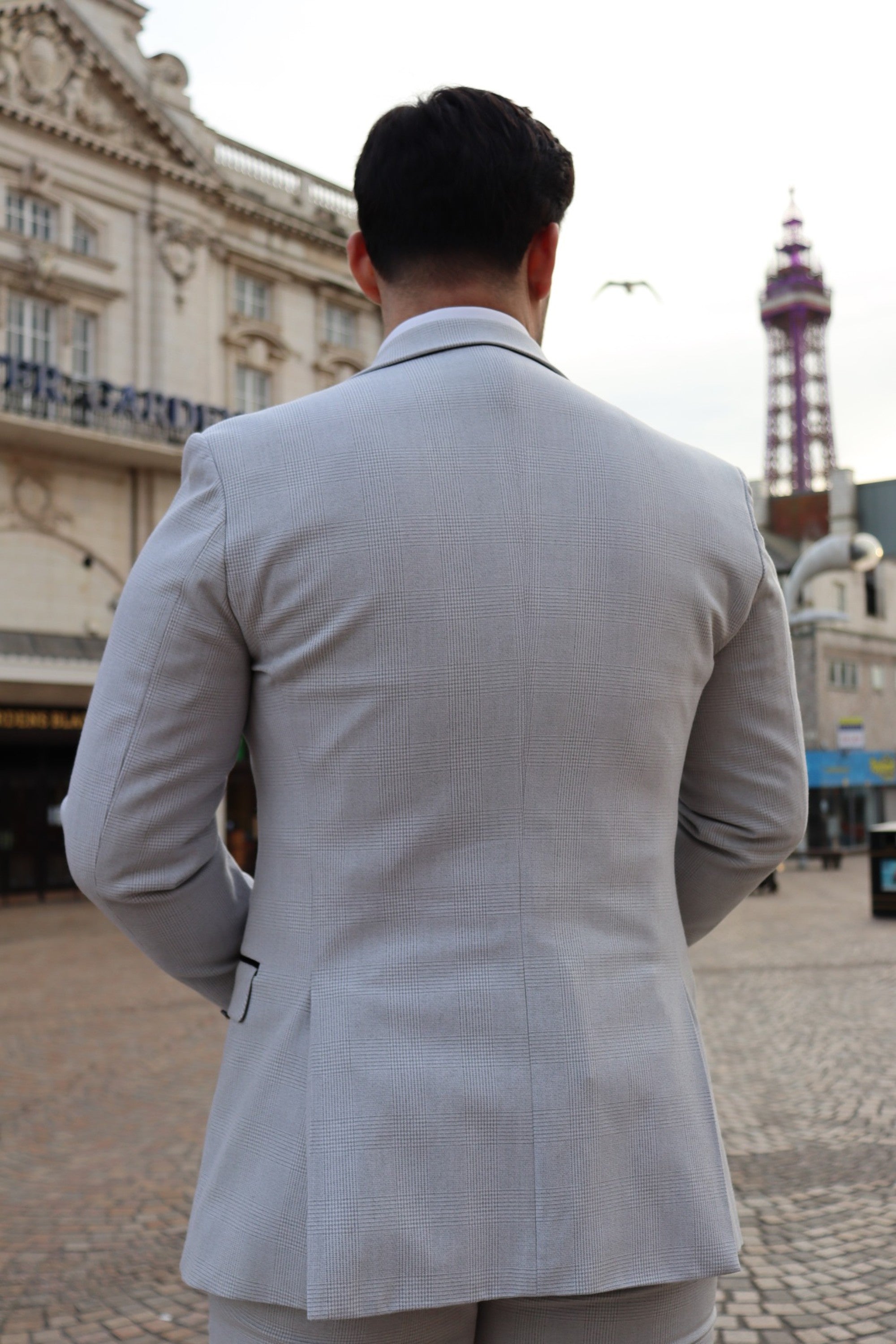 Model wearing the SUITBAE Charles Stone Three-Piece Suit — striking stone tone for spring weddings and race days.