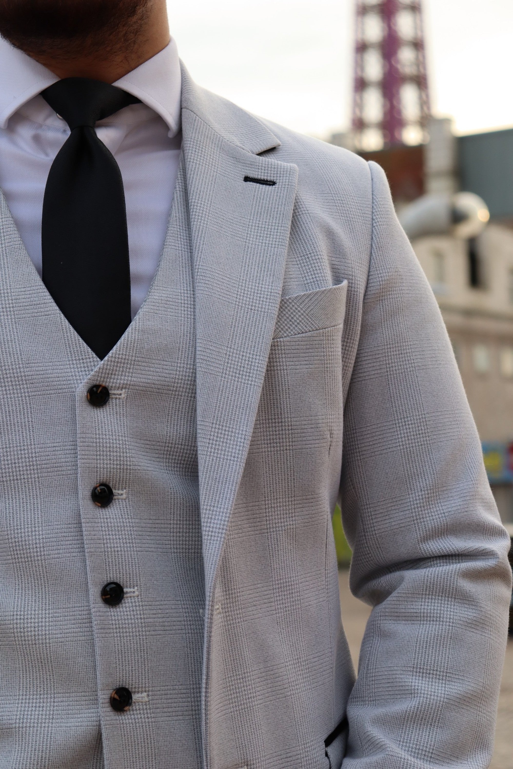 Close-up of the SUITBAE Charles Stone Three-Piece Suit in light stone grey, featuring a black tie, peak lapel blazer, and matching waistcoat — a refined choice for weddings, races, and formal events.
