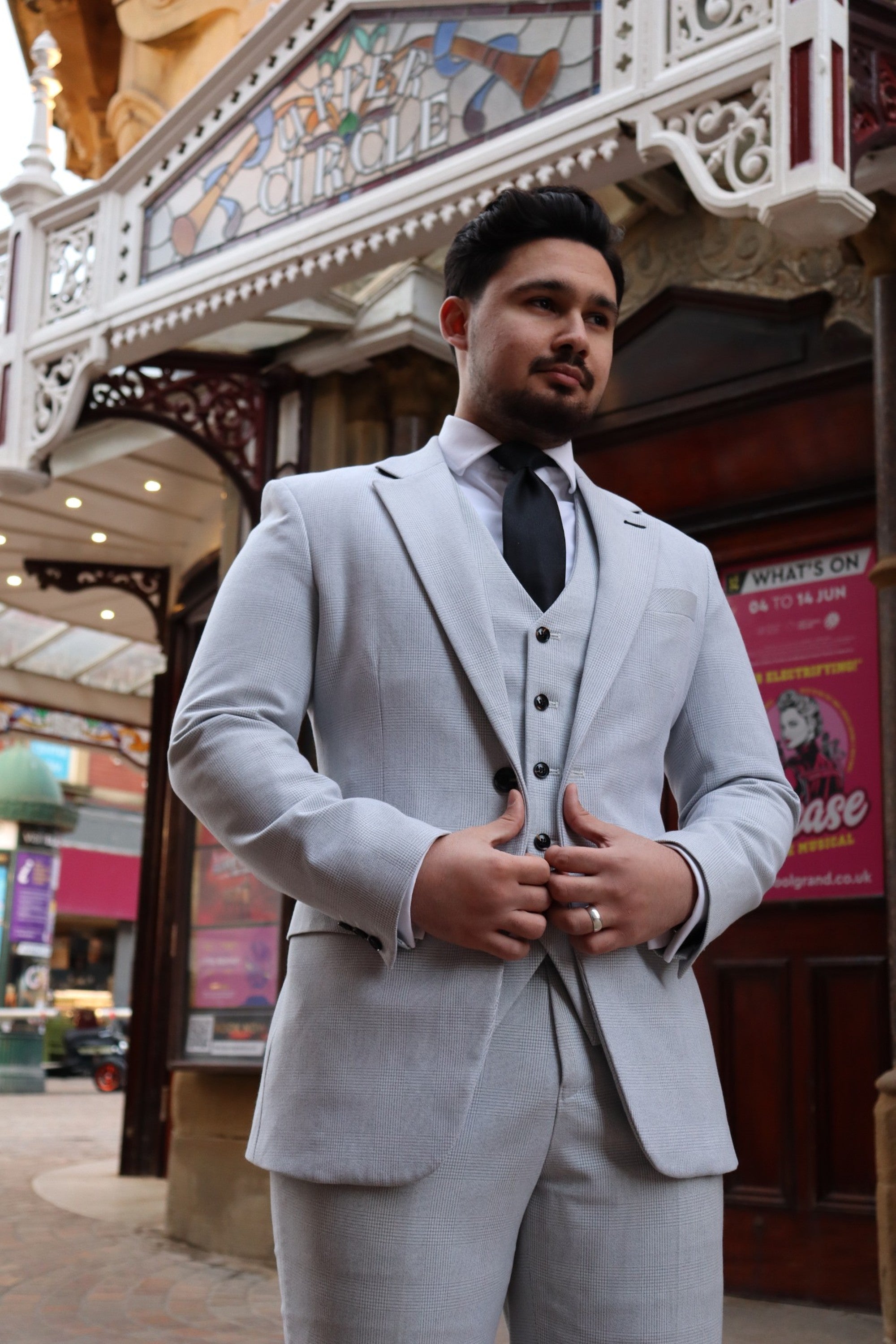 Wedding guest in a beige or stone SUITBAE suit at an outdoor summer wedding.